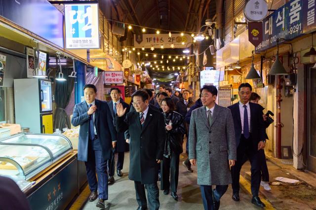  이재명 대통령이 9일 저녁 식사를 위해 방문한 서울 종로구 통인시장에서 상인들에게 인사하고 있다 사진연합뉴스