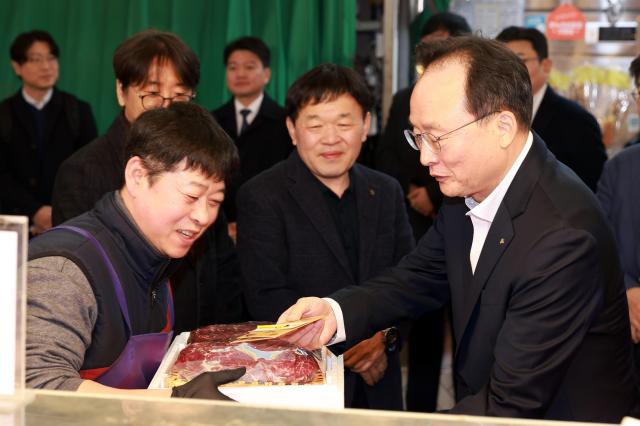 11일 망원시장에서 열린 ‘2026 설맞이 전통시장 사랑나눔’ 행사에서 이환주 KB국민은행장이 식료품을 구입하고 있다

