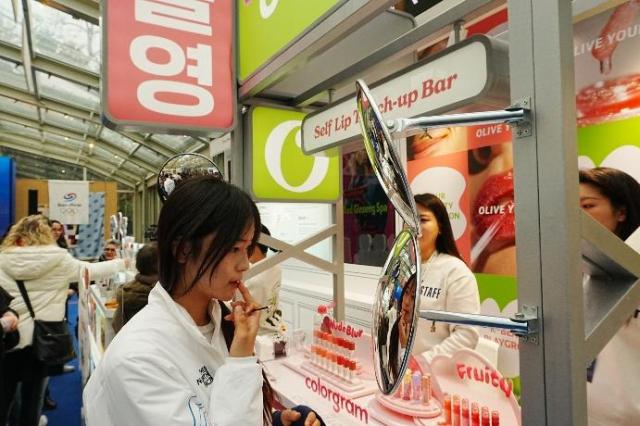 스노보드 하프파이프 금메달 최가온이 밀라노 코리아하우스 ‘올리브영’ 부스에서 립 제품을 테스트하고 있다 사진CJ그룹