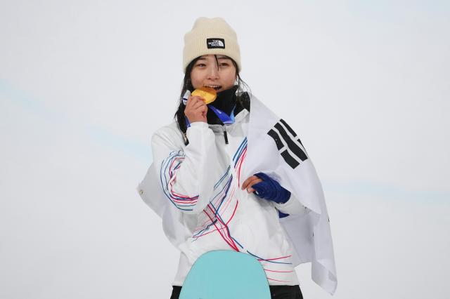Gold medalist South Koreas Choi Ga-on bites her medal after winning the womens snowboarding halfpipe finals at the 2026 Winter Olympics in Livigno Italy Thursday Feb 12 2026 APYonhap