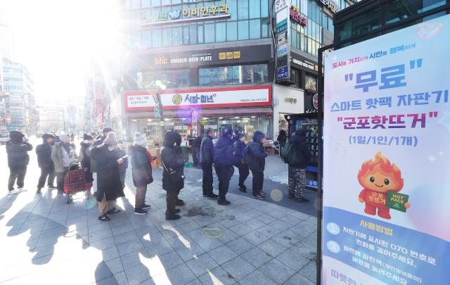 경기도 군포시 산본 로데오거리에 설치된 스마트 핫팩 자판기 군포 핫뜨거에서 시민들이 무료 핫팩을 받기 위해 줄을 서 있다사진연합뉴스 

   