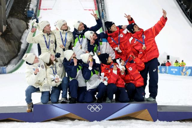 Gold medalists Team Slovenia silver medalists Team Norway and bronze medalists Team Japan take a victory selfie during the ski jumping mixed team medal ceremony at the Milano Cortina 2026 Winter Olympics at Predazzo PSJ-Normal Hill Italy Courtesy of Samsung Electronics