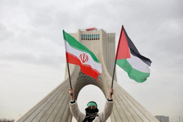 지난 11일현지시간 이란 테헤란에서 이슬람 혁명 47주년 기념 행사 중 아자디 타워 근처에서 한 사람이 이란 국기와 팔레스타인 국기를 들고 있다 사진로이터·연합뉴스