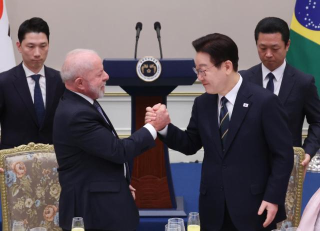 South Korean President Lee Jae Myung right holds hands with Brazilian President Luiz Inacio Lula da Silva after Lula left delivers his return speech during a state dinner at Cheong Wa Dae on Feb 23 YONHAP