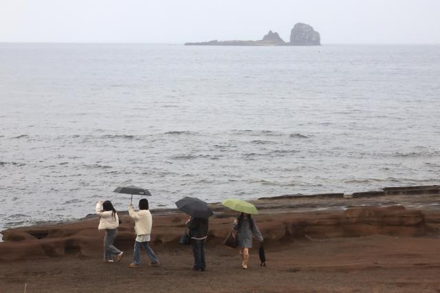 10일 오전 제주 서귀포시 안덕면 사계리 해안을 찾은 관광객이 우산을 들고 바닷가 정취를 즐기고 있다 사진연합뉴스