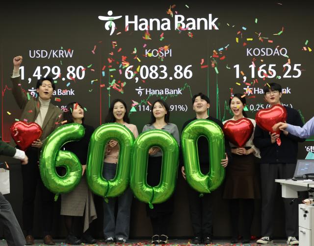 코스피가 사상 처음으로 6000포인트를 돌파한 25일 장 마감 후 서울 중구 하나은행 딜링룸에서 딜러들이 축하하고 있다 사진연합뉴스