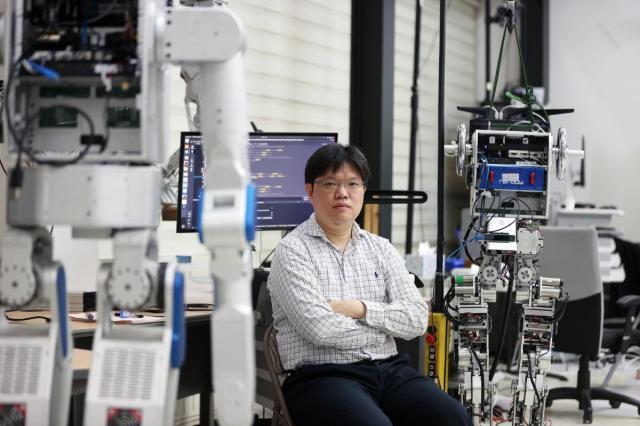 Park Hae-won professor of robotics at KAISTs Dynamic Robot Control and Design Laboratory poses for a photo among HUBO models Courtesy of KAIST
