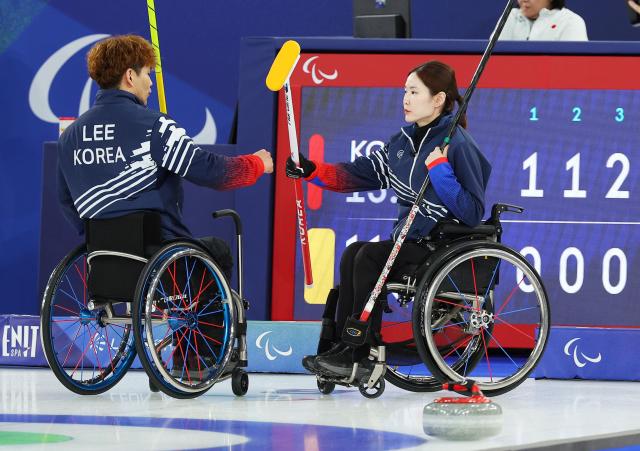 Lee Yong-seok and Baek Hye-jin of South Korea celebrate after winning the third end during the wheelchair curling mixed doubles preliminary match between South Korea and Japan at the Cortina Curling Olympic Stadium in Cortina Italy at the 2026 Milan–Cortina Winter Paralympics on Mar 5 2026 local time Yonhap 20260306