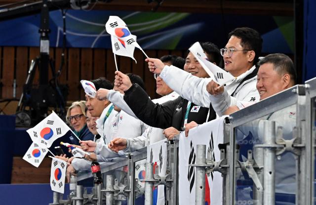 Jeon Seon-ju right head of the athletes’ village and Yang Oh-yeol head of the South Korean delegation cheer while holding the national flag during the wheelchair curling mixed doubles preliminary match between South Korea and Japan at the Cortina Curling Olympic Stadium Stadio Olimpico del Ghiaccio in Cortina d’Ampezzo Italy at the 2026 Milan–Cortina Winter Paralympics on Mar 5 2026 local time Photo pool 20260306