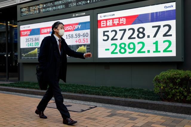 9일 일본 도쿄에 있는 증시 전광판 앞을 한 행인이 걸어가고 있다사진EPA연합뉴스