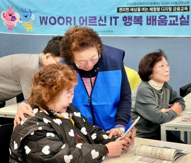 우리 어르신 IT 행복 배움교실에서 전년도 우수 수강생이 보조강사로 활동하며 다른 수강생들을 돕고 있는 모습 사진우리금융
