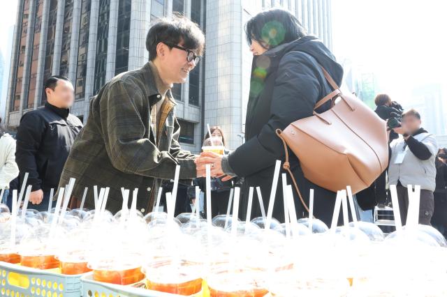 Director Jang Hang-jun hands a cup of coffee to a citizen during a coffee truck event held to thank audiences for the box-office success of the film The King and the Man Who Lives at the Korea Press Center Plaza in central Seoul on March 12 2026 Yonhap 20260312