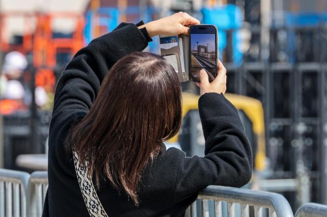 A citizen takes photos of stage installation at Gwanghwamun Square in Jongno District central Seoul four days ahead of the Gwanghwamun performance by K-pop group BTS March 17 2026 AJP Yoo Na-hyun 20260317
