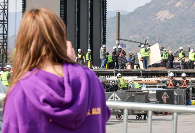 A foreign tourist watches the stage installation for the upcoming BTS performance at Gwanghwamun Square in Jongno District Seoul March 18 2026 AJP Yoo Na-hyun 20260318