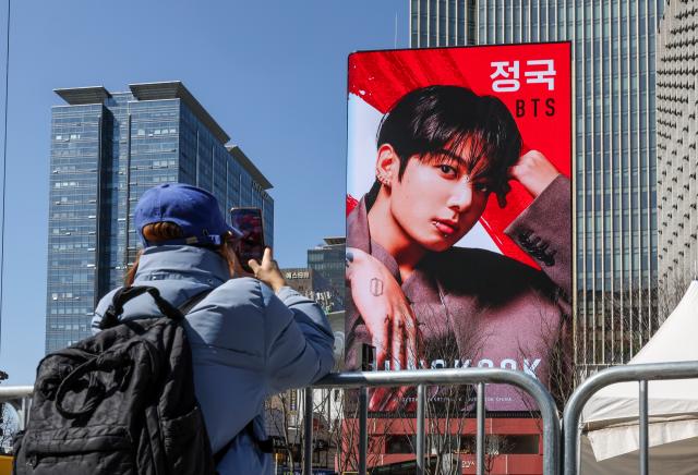 A fan takes a photo of BTS Jungkook on a digital billboard at Gwanghwamun Plaza in Seoul March 19 2026 AJP Yoo Na-hyun 20260319