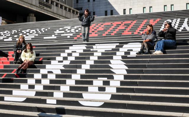 Fans pose for a photo on the steps of Sejong Center for the Performing Arts displaying a message announcing BTSs comeback in Seoul March 19 2026 AJP Yoo Na-hyun 20260319