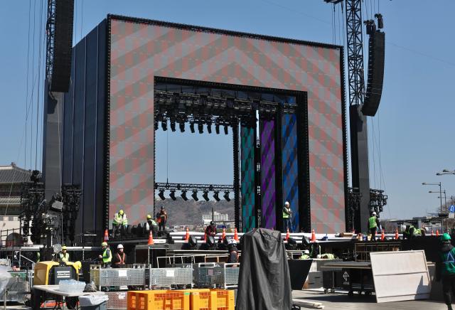 Construction continues as the day progresses The photo shows the assembled stage with lighting and video panels being tested March 19 2026 AJP Han Jung-gu