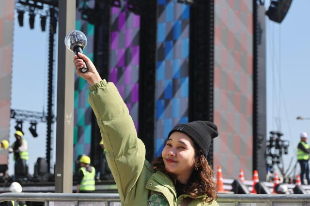 Some fans are taking photos in front of the stage with their light stick as the construction continues March 19 2026 AJP Han Jung-gu