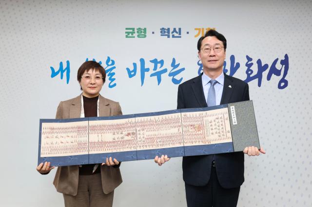 정명근 화성특례시장과 샤오간시 대표단이 방문기념품인 ‘정조대왕 화첩’을 들고 기념촬영을 하고 있다 사진화성시