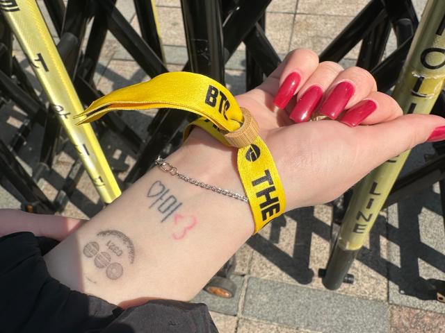 An ARMY shows a tattoo reading ARMY in Korean on their arm while waiting for the BTS concert at Gwanghwamun Plaza in Seoul March 21 2026