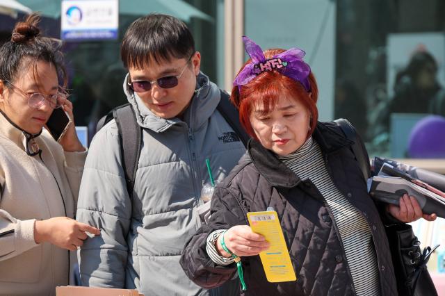 An ARMY looks at merchandise while waiting for the BTS concert at Gwanghwamun Plaza in Seoul March 21 2026 AJP Yoo Na-hyun