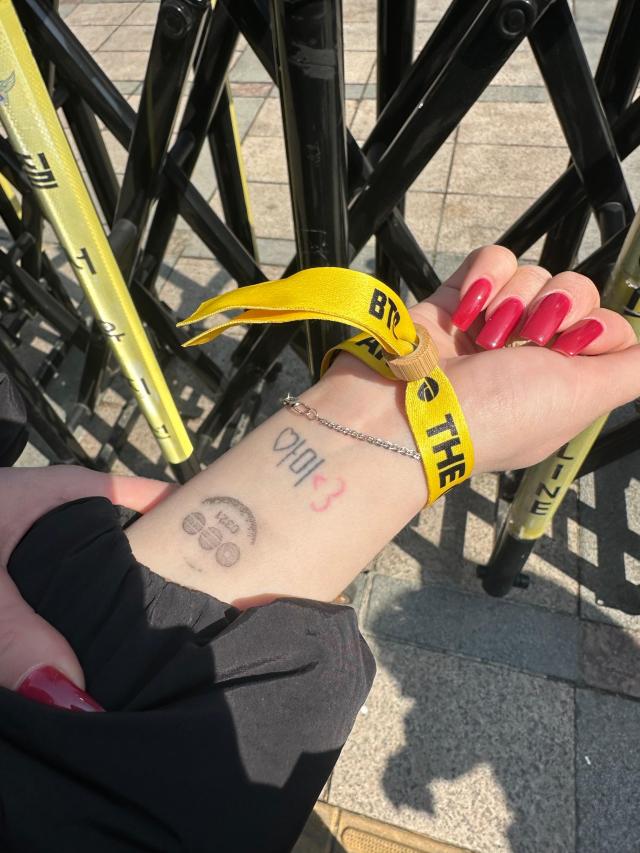 Ami Ostrovskaia 23 Russia who is a BTS fan shows a tattoo and wristband at the comeback event venue in Seoul on March 21 2026 AJP Kim Hee-su

