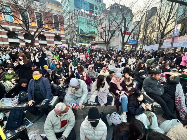 Fans finding any place to seat in front of digital screens along Gwanghwamum on March 21 2026  Han Jun-gu