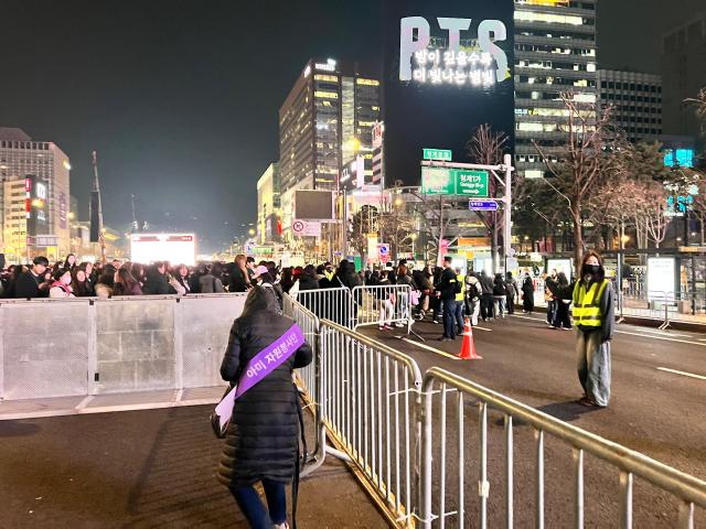 An ARMY volunteer guides crowds released from BTS comeback concert in central Seoul helping them move toward the Cheonggyecheon area following the conclusion of the performance AJP Yoo Joon-ha