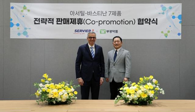 Bukwang Pharm CEO Lee Je-young, right, and Servier Korea CEO Olivier Rousseau pose after signing a co-promotion agreement