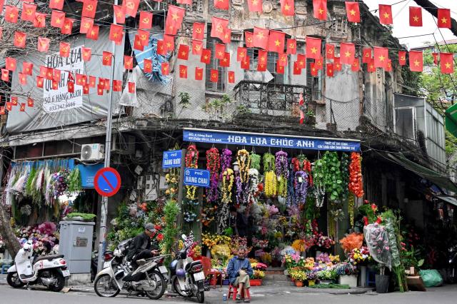 Men look at their their phones as they sit in front of a flower shop in Hanoi on Mar 5 2026 AFP-Yonhap
