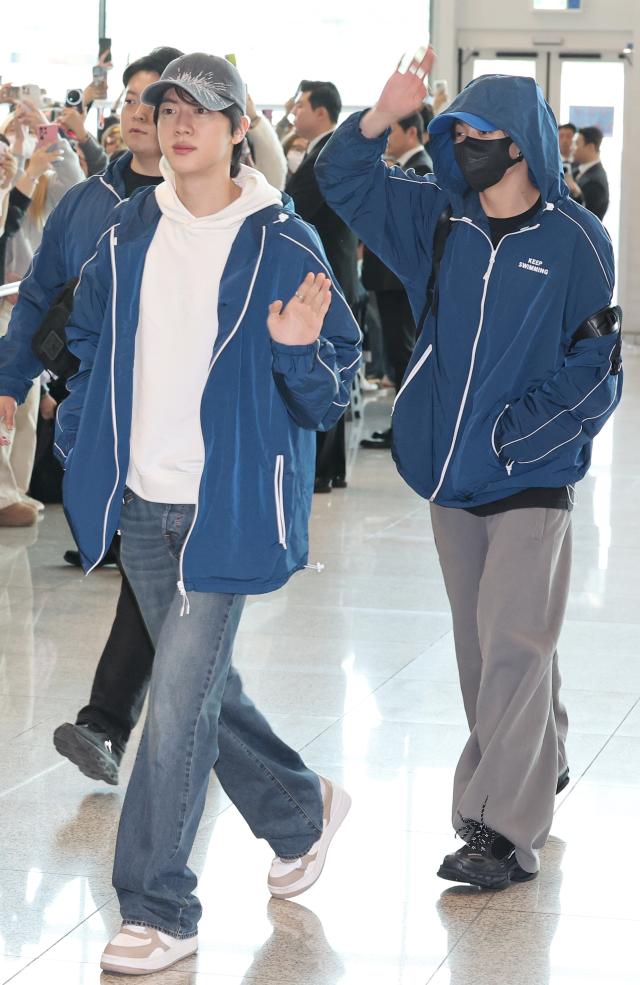BTS members Jin left and Jungkook depart through Incheon International Airport for a Spotify performance in New York March 22 2026
