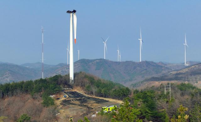 Stationary wind turbines are visible beyond a wind turbine that was charred black by fire the previous day at the Changpo Wind Farm in Yeongdeok County North Gyeongsang Province March 24 Yonhap