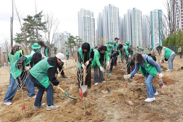 Participants plant trees during a tree-planting event marking the 81st Arbor Day at Daeyupyeong Park in Jangan-gu Suwon Gyeonggi Province on March 31 2026 Yonhap