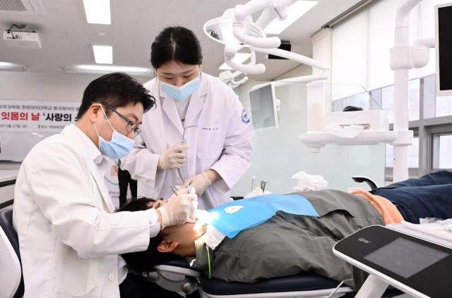 Members of the Korean Academy of Periodontology and students from Hanyang Women’s University’s dental hygiene department provide free scaling services. [Photo=Dongkook Pharmaceutical]