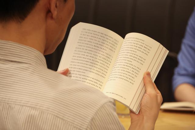 A participant is reading a book at an “Admin Night” session at a café in Gwanak District Seoul March 31 2026 AJP Yoo Na-hyun