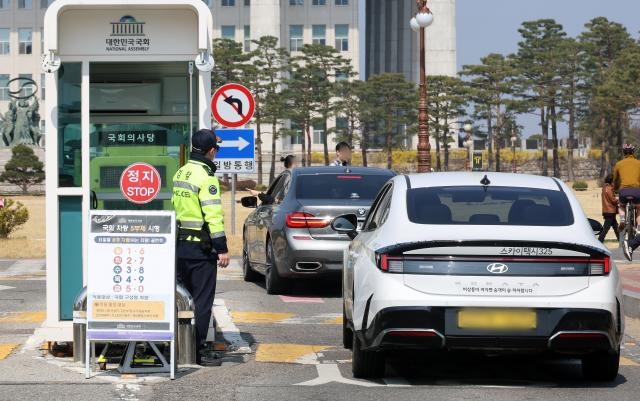 공공기관 차량 5부제 시행 첫날인 3월 25일 서울 여의도 국회 정문에서 경찰이 운전자에게 우회로를 안내하고 있다사진연합뉴스