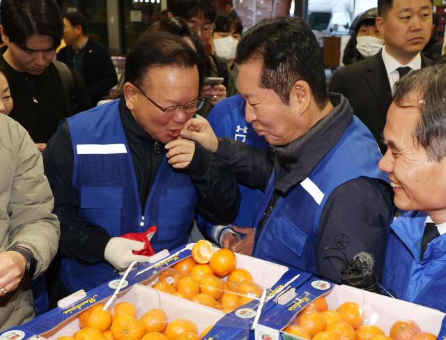 정청래 더불어민주당 대표와 민주당의 대구시장 후보로 확정된 김부겸 전 총리가 8일 오전 대구 북구 매천동 농수산물도매시장을 찾아 민생현장을 살피며 귤을 맛보고 있다 사진연합뉴스