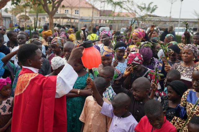 A Catholic priest sprinkles water on faithfuls carrying palm fronds commemorating Palm Sunday outside St Micheals Cathedral church in Minna  Nigeria March 29 2026 AP-Yonhap 