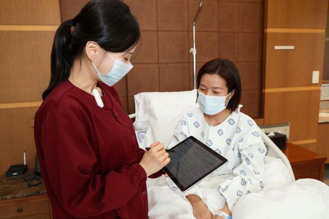 서울성모병원 간호사가 태블릿을 활용하여 환자와 모바일 간호정보를 확인하고 있다사진서울성모병원