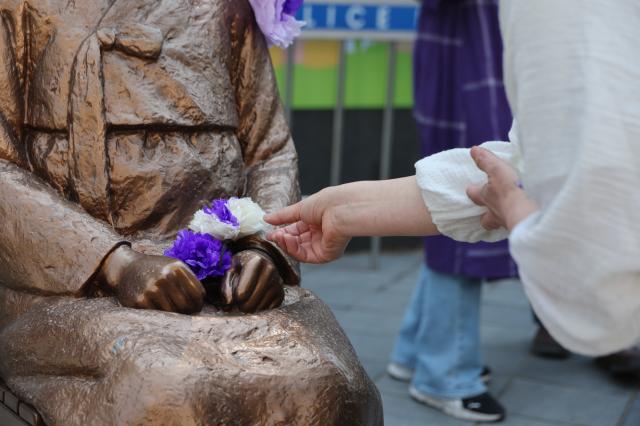 A participant lays artificial flowers at the Statue of Peace in front of the former Japanese Embassy in Jongno-gu Seoul April 8 2026 AJP Han Jun-gu