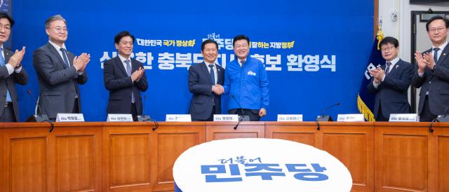 더불어민주당 충북도지사 후보로 확정된 신용한 대통령 직속 지방시대위원회 부위원장이 14일 국회에서 열린 환영식에서 정청래 대표가 전달한 파란색 당 점퍼를 입은 뒤 악수하고 있다사진연합뉴스