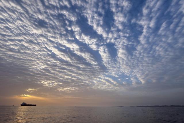 The sun rises behind a tanker anchored in the Strait of Hormuz off the coast of Qeshm Island Iran Saturday April 18 2026 AP-Yonhap 