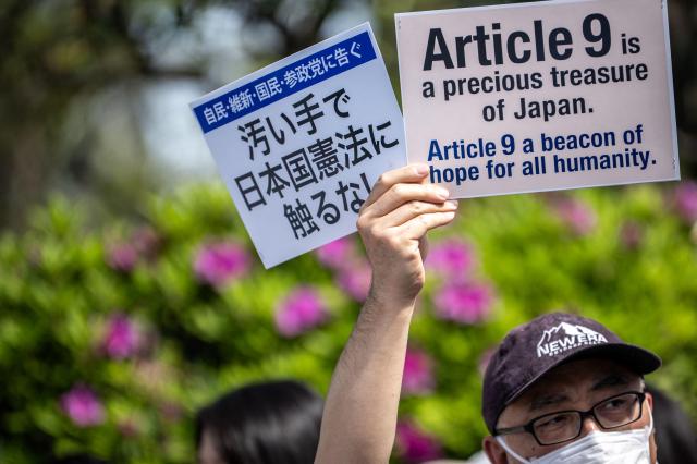 A man holds placards during the No war Dont change the Constitution rally outside the main gate of the National Diet Building in Tokyo on April 19 2026 AFP-Yonhap
