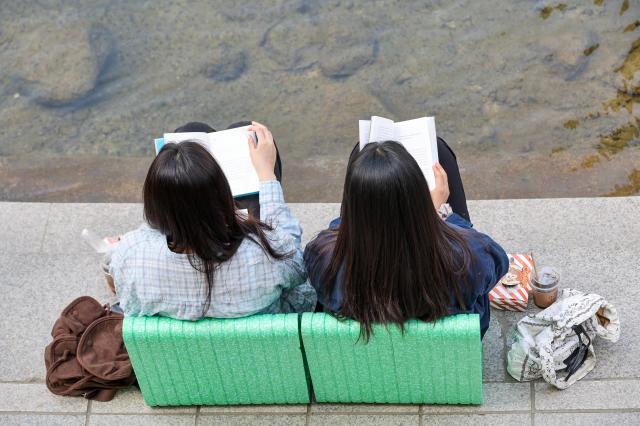 Citizens read books at the “Reading Clear Stream” outdoor library along Cheonggyecheon Stream in central Seoul on April 23 2026 as the city launched its outdoor library program on World Book and Copyright Day AJP Yoo Na-hyun
