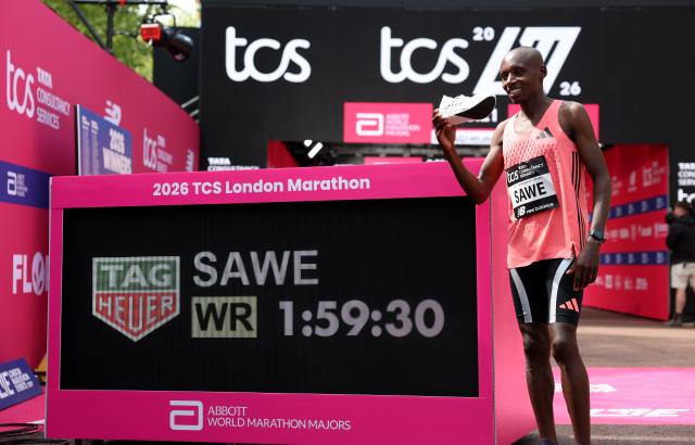 Kenya’s Sebastian Sawe poses beside a display showing his world record at the 2026 London Marathon in London on April 26. Photo: Yonhap via Reuters
