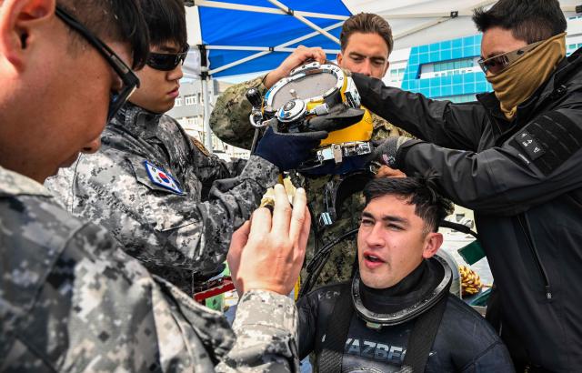Republic of Korea Navy Sea Salvage and Rescue Unit SSU deep-sea divers check the condition of a US Navy Mobile Diving and Salvage Unit MDSU diver after completing surface-supplied diving system training during a joint rescue exercise in the Jinhae Bay area of South Gyeongsang Province April 8 2026 Yonhap 