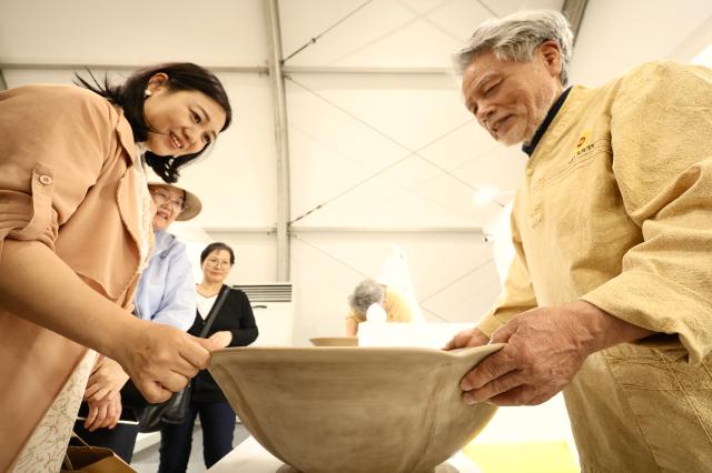 A visitor touches ceramics by master craftsman Choi In-gyu at the Icheon Ceramic Festival held in Sindun-myeon Icheon April 29 2026 AJP Han Jun-gu
