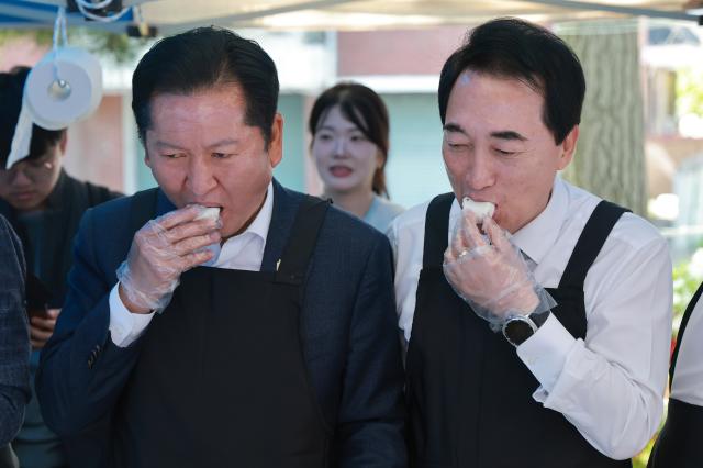 정청래 더불어민주당 대표왼쪽와 박수현 민주당 충남도지사 후보가 1일 충남 서산시 문화회관에서 음식을 준비하던 중 떡을 맛보고 있다 사진연합뉴스
