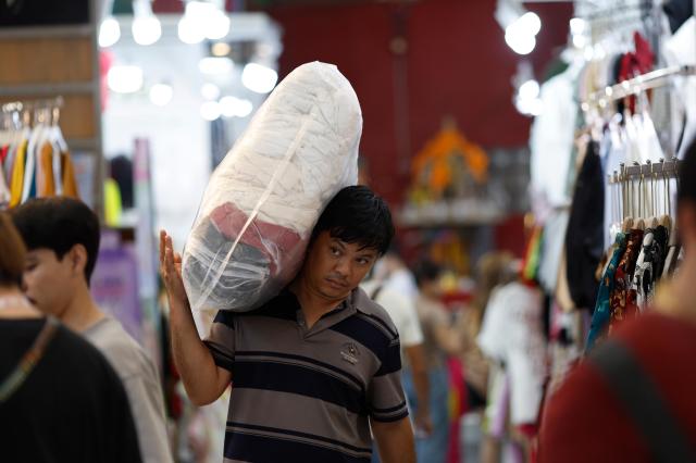 A worker carries a bag of clothes at Pratunam wholesale garment market in Bangkok Thailand 20 April 2026 The International Monetary Fund revised down Thailands economic expansion projection to 15 per cent from the previously projected 16 per cent which will be the slowest economic growth in ASEAN due to the Middle East war EPA-Yonhap 