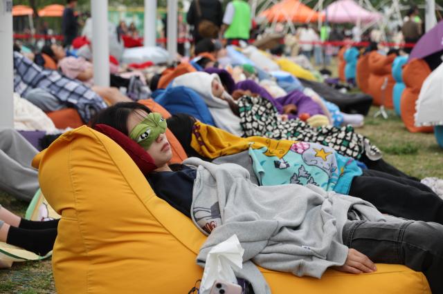Participants sleep during the 2026 Hangang Sleeping Contest on May 2, 2026, at the Multi Plaza of Yeouido Hangang Park in Seoul’s Yeongdeungpo District.
